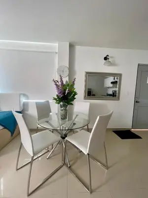 a glass table with white chairs and a vase of flowers at Apartamentos cerca al hotel Las Americas in Cartagena de Indias