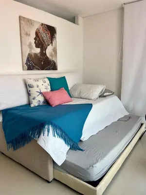 a bed with colorful pillows on it in a room at Apartamentos cerca al hotel Las Americas in Cartagena de Indias