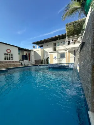 a swimming pool with a water fountain in front of a house at Casa Campestre Valle del Mar in Santa Marta