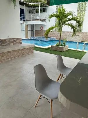 two chairs and a table in a building with a pool at Casa Campestre Valle del Mar in Santa Marta