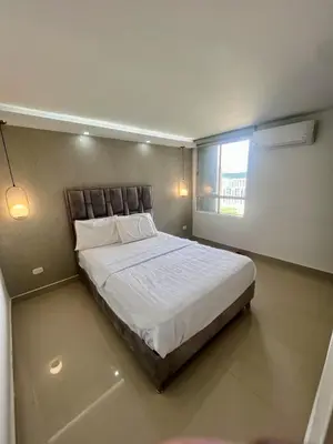 a bedroom with a large white bed with a window at Nuevo apartamento de lujo con balcón wifi AC piscina in Barranquilla