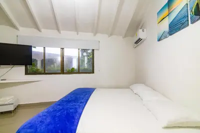 a white bedroom with a bed and a flat screen tv at Casa de playa vistamare in Santa Marta