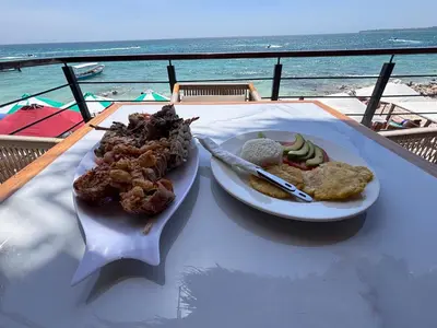 a plate of food on a table next to the ocean at Euphoria Beach in Playa Blanca