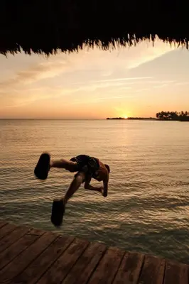 a man jumping off a dock into the water at Hotel isla bonita in Tintipan Island