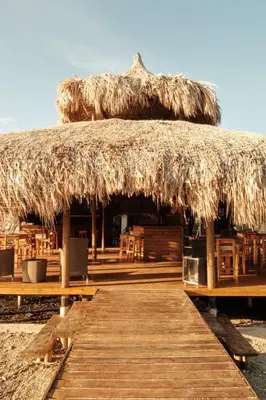 a hut with a straw roof with tables and chairs at Hotel isla bonita in Tintipan Island