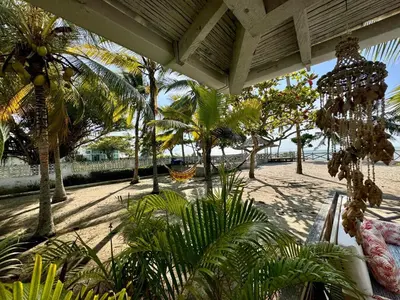 a patio with palm trees and a hammock on a beach at Casa de playa rústica en Tolú in San Silvestre