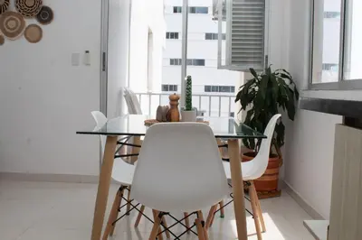 a dining room with a glass table and white chairs at Encantador Apartamento El Laguito Bocagrande in Cartagena de Indias