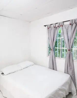 a white bed in a room with a window at Apartamento hostal oasis 2 in Puerto Colombia