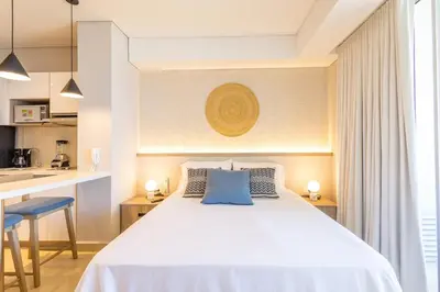 a bedroom with a large white bed with blue pillows at Cosy seaside studio with sunset view in Cartagena de Indias