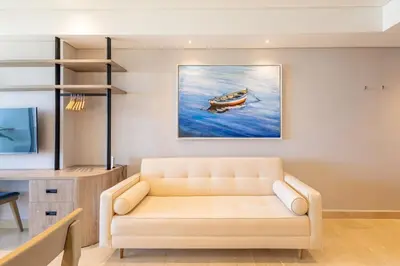 a living room with a couch and a painting of a boat at Cosy seaside studio with sunset view in Cartagena de Indias