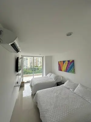 two beds in a white room with a window at Acogedor apartamento en Bello Horizonte in Santa Marta