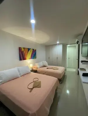 a hotel room with two beds and a tv at Acogedor apartamento en Bello Horizonte in Santa Marta