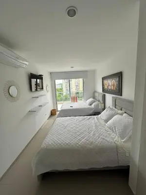 a white bedroom with two beds and a window at Acogedor apartamento en Bello Horizonte in Santa Marta