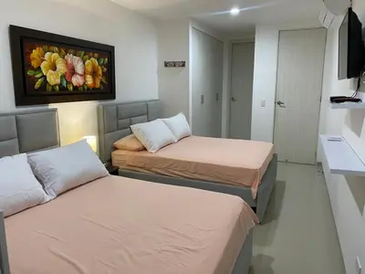 a room with two beds and a painting on the wall at Acogedor apartamento en Bello Horizonte in Santa Marta