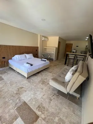 a bedroom with a bed and a couch and a kitchen at Forest Condominio in Coveñas