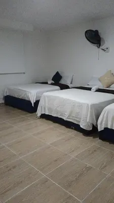 two beds in a room with wooden floors at Prado alto inn in Barranquilla