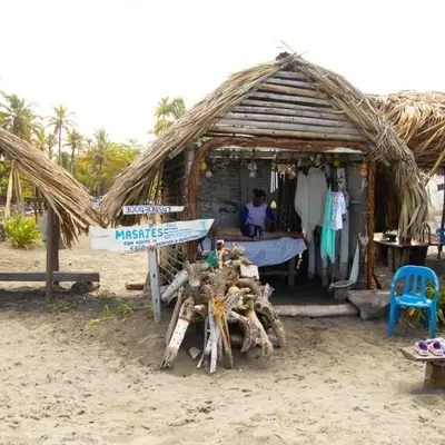 a hut on the beach with a woman sitting in it at Cabañas Capilla Del Mar in San Bernardo del Viento