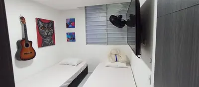a small room with a bed and a guitar and pictures at Apto para 6, cerca a la ciudad amurallada in Cartagena de Indias