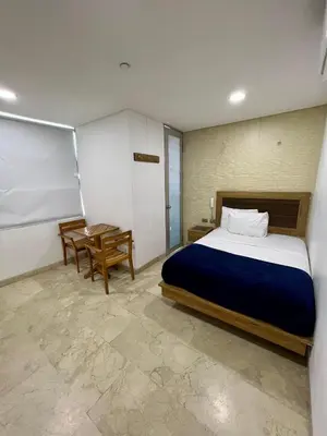 a bedroom with a large bed and a table at Hotel Odonata Real in Cartagena de Indias