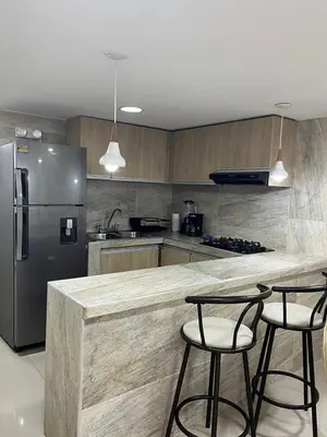 a kitchen with a stainless steel refrigerator and two bar stools at Acogedor y Moderno Apartamento en Barranquilla in Barranquilla