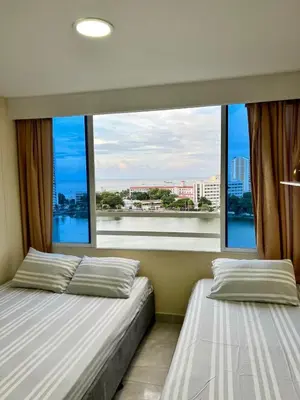 two beds in a room with a large window at Apartamentos Por dias Laguito Ctg in Cartagena de Indias