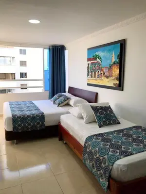 a bedroom with two beds and a painting on the wall at Apartamentos Por dias Laguito Ctg in Cartagena de Indias