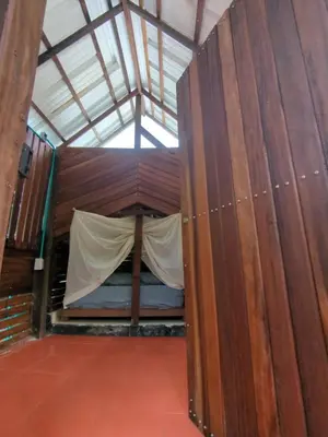 a small room with a bed in a wooden wall at Lala's Place in Isla Fuerte