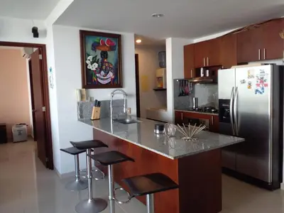 a kitchen with a stainless steel refrigerator and stools at 2MV-5G Apartamento de 2 Alc Vista al mar con A A Piscina y Wifi in Cartagena de Indias