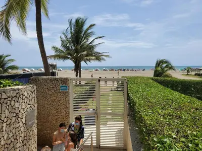 two people walking through a gate at the beach at 2MV-5G Apartamento de 2 Alc Vista al mar con A A Piscina y Wifi in Cartagena de Indias
