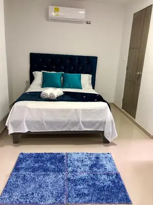 a bedroom with a bed with blue rugs on it at Hostal Asturias Real in Barranquilla