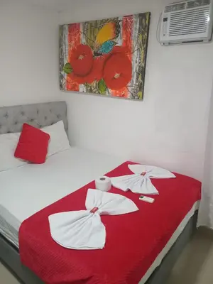 a bedroom with a bed with a red blanket at Hostal Asturias Real in Barranquilla