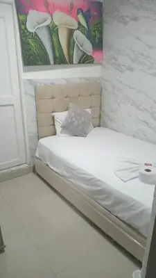 a bed in a room with a painting on the wall at Hostal Asturias Real in Barranquilla