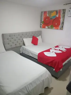 two beds in a room with a red blanket at Hostal Asturias Real in Barranquilla