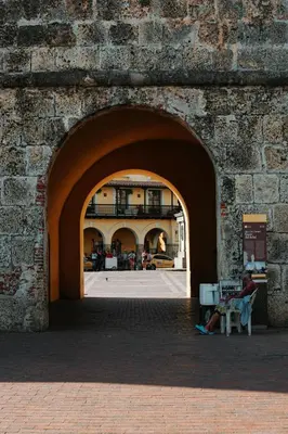 an archway in a brick wall with a person sitting on a chair at Tranquila y cerca de la magia in Cartagena de Indias