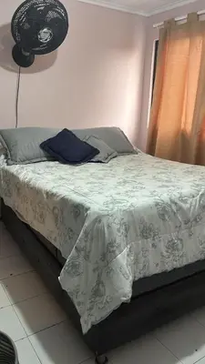 a bedroom with a bed with a gray and white comforter at Habitacion en el Norte cerca al Malecón in Barranquilla