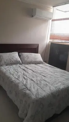a bedroom with a bed with a white comforter and a window at Habitacion en el Norte cerca al Malecón in Barranquilla