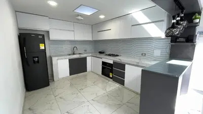 a kitchen with white cabinets and a black refrigerator at Casa Elena in Tolú