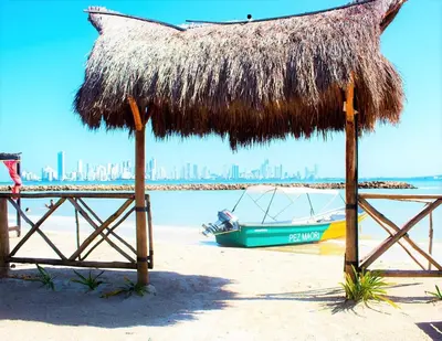 a straw umbrella and a boat on a beach at Cabaña Mary Mar en Isla in Cartagena in Isla de Tierra Bomba