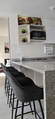 a kitchen with a counter with four black chairs at SERENA REST Conjunto Capriella Cartagena in Manzanillo del Mar