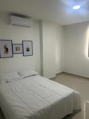 a bedroom with a white bed with pictures on the wall at Aparta suite in Cartagena de Indias