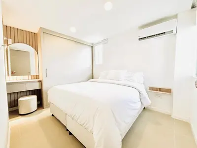 a white bedroom with a white bed and a mirror at Splendid condo with a sea view in Puerto Colombia