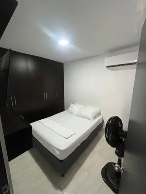 a small bedroom with a white bed and a black cabinet at ruiseñor 1 in Barranquilla