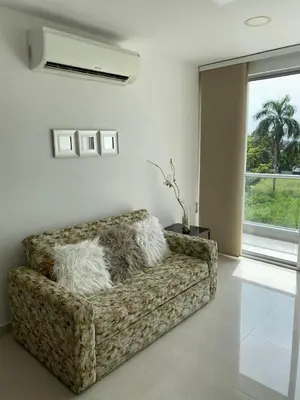 a couch sitting in a living room with a window at 1 bedroom apartment close to the beach in Cartagena de Indias