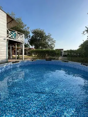 a large pool of blue water in front of a house at Ikako beach club in Cartagena de Indias