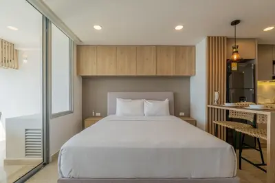a bedroom with a large white bed and a kitchen at Suite 15th floor con vista mar y piscina CB1511 in Cartagena de Indias