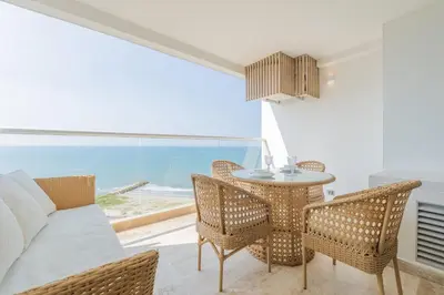 a living room with a table and chairs and a view of the ocean at Suite 15th floor con vista mar y piscina CB1511 in Cartagena de Indias