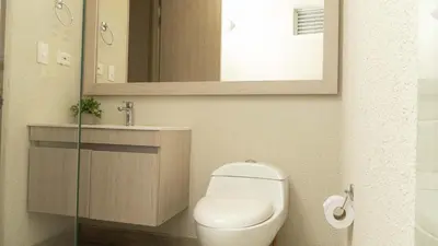 a bathroom with a toilet and a sink and a mirror at New & Comfortable Apartment 2 BR In Cielo Mar in Cartagena de Indias