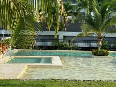 a swimming pool with palm trees in front of a building at Apartamento en Playa Manzanillo in Cartagena de Indias
