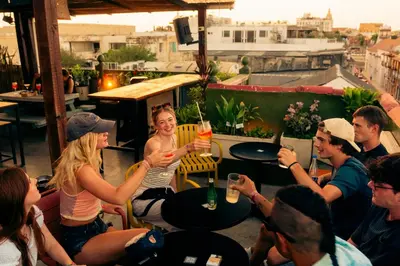 a group of people sitting around a table on a rooftop at Viajero Cartagena - Getsemaní Hostel in Cartagena de Indias