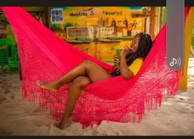 a woman sitting in a hammock talking on a cell phone at TESORO de BARU in Cartagena de Indias